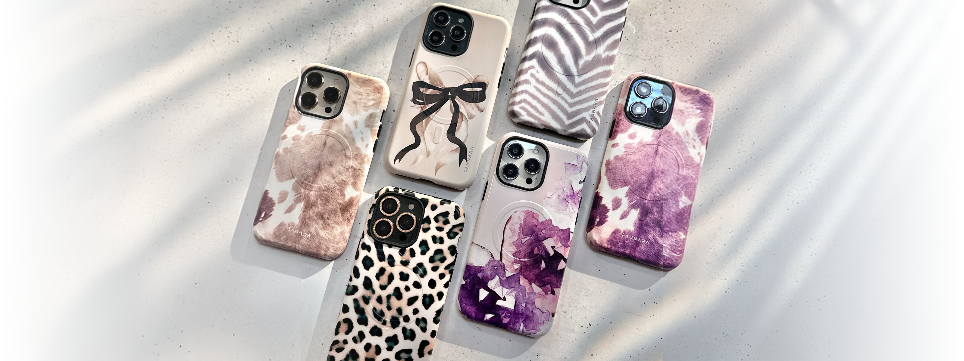 Phone case lineup with tie-dye, zebra, and floral patterns on a gray tray, showing camera cutouts.